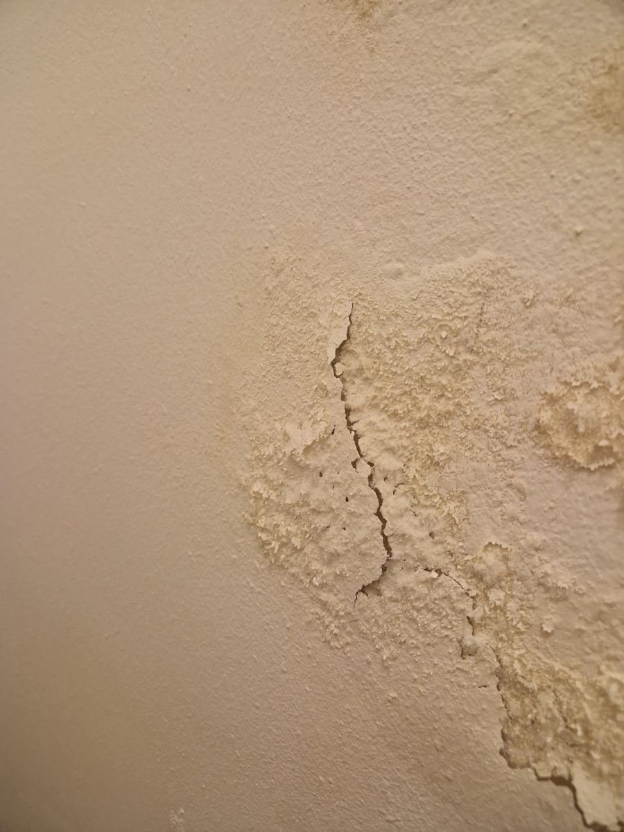 Afbladderende verf en scheur in een muur door vocht
